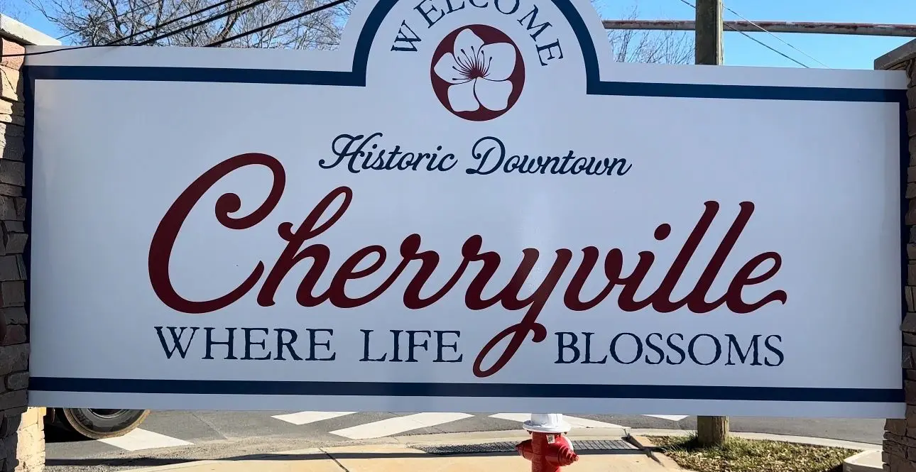 A sign reads "Welcome Historic Downtown Cherryville Where Life Blossoms" with a cherry blossom graphic in the center.