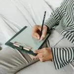 A stock photo of a woman writing on a notepad.