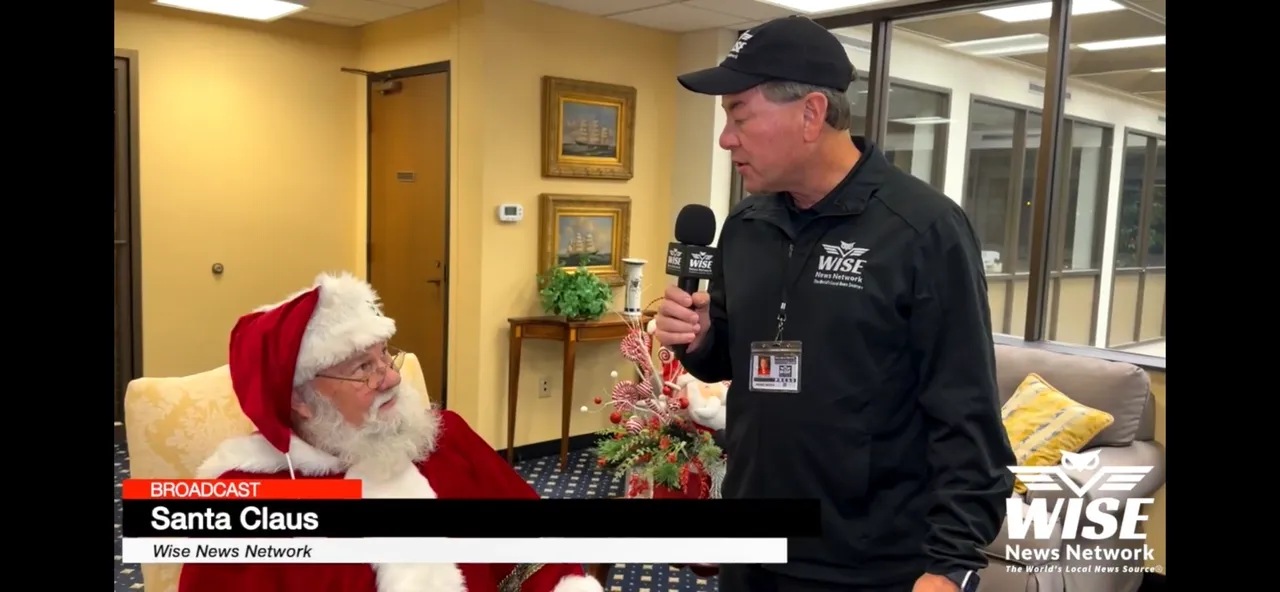 A man dressed as Santa Claus is being interviewed by a man holding a microphone from WISE News Network.