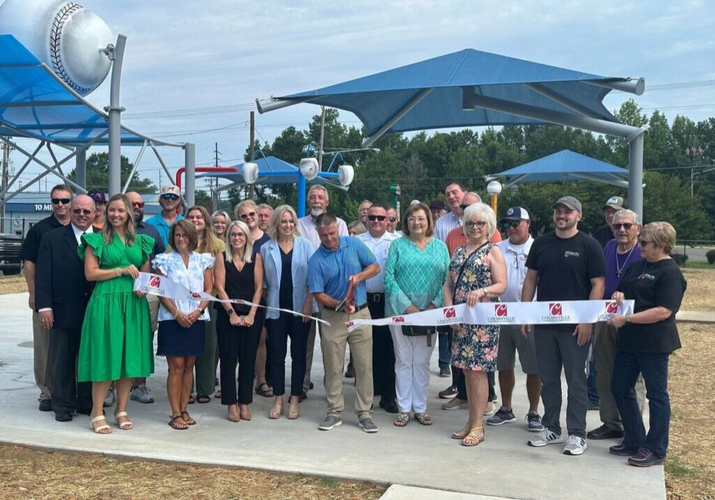 A group of people standing around cutting the ribbon.