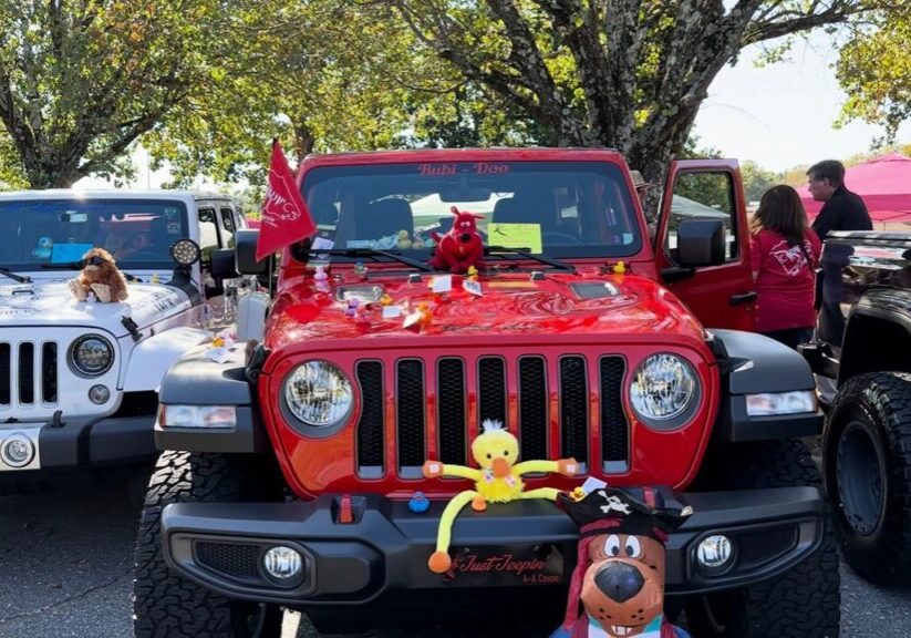 A red jeep with decorations on the hood.